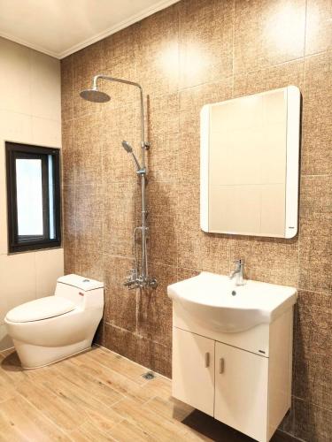 a bathroom with a toilet and a sink and a shower at Xinyuanbao Shangshi Homestay in Donggang