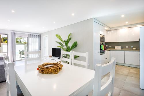 a kitchen and dining room with a white table and chairs at Kasino II RC Q in Monte Gordo