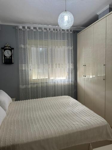 a bedroom with a bed and a window with a clock at Roy Apartments in Durrës