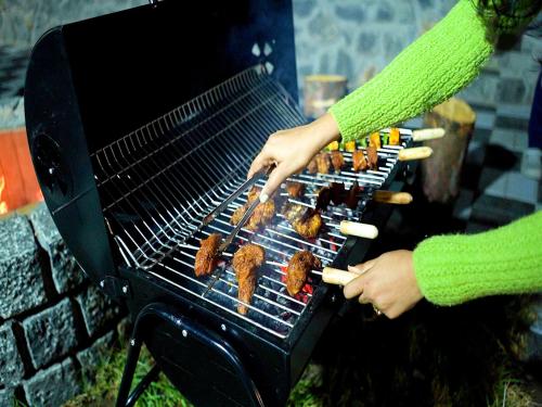 a person is cooking food on a grill at The Jade Highlands Mountain View 2 bhk Villa in Kodaikānāl