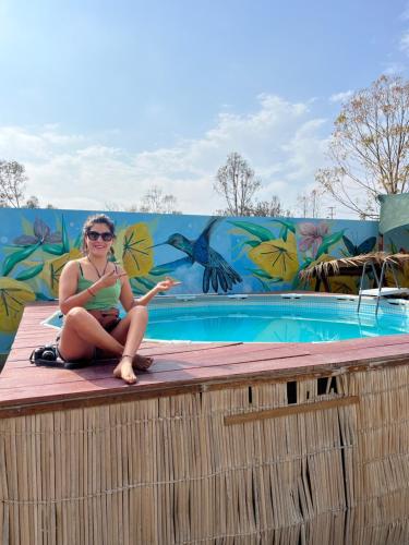 una mujer sentada en el borde de una piscina en Paracas Camp Lodge & Experiences, en Paracas
