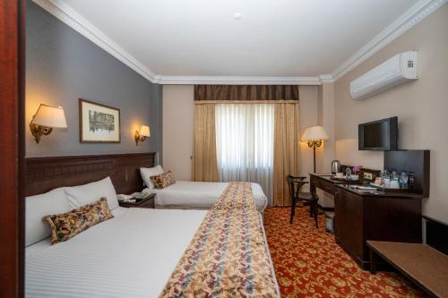 a hotel room with two beds and a desk at Pera Rose Hotel - Taksim Pera in Istanbul