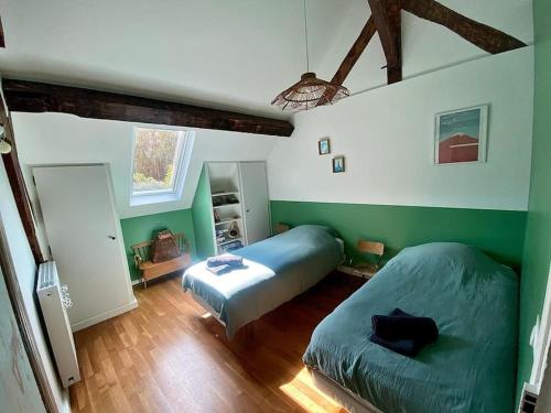 2 letti in una camera da letto con pareti verdi e pavimenti in legno di ARconciergerie Évasion en Pleine Nature a Boigneville