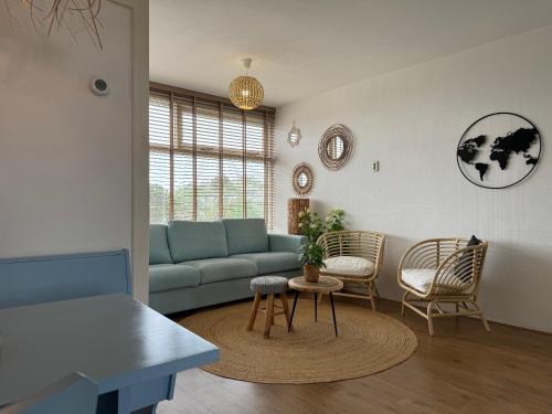 - un salon avec un canapé bleu et des chaises dans l'établissement die Perle, à Zandvoort