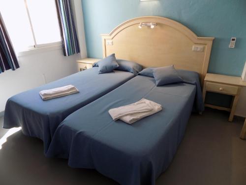 Dos camas en una habitación de hotel con toallas. en Hostal Villa Maruja, en El Arenal