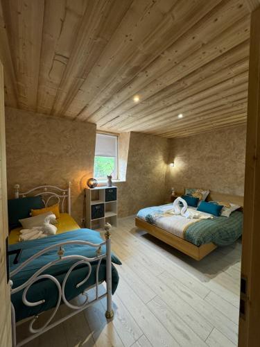 une chambre avec deux lits et un plafond en bois dans l'établissement La petite fille des rivières, à Foncine-le-Bas