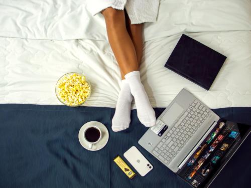 a woman laying on a bed with a laptop and a cup of coffee at Hotel America Chiclayo in Chiclayo