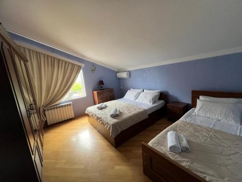 a bedroom with two beds and a window at Guesthouse Emilya in Kutaisi