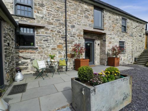 a stone building with a courtyard with flowers in a pot at Plas Glan Yr Afon in Abergele