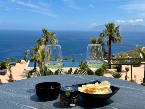 a table with two glasses of white wine and chips at Baglio La Porta by Geocharme in San Vito lo Capo