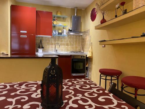 una cucina con armadi rossi e 2 sgabelli di La Casa dei Fieschi a Lavagna