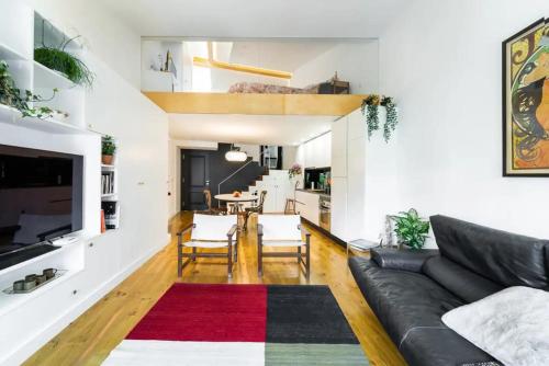 a living room with a black couch and a red rug at Casa Velhinha - Design, Culture and Comfort in Guimarães in Guimarães