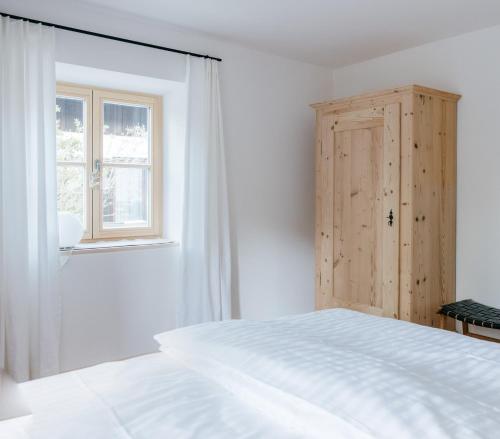 a white bedroom with a bed and a window at Haus Herzogstand - Ferienwohnungen in Kochel am See in Kochel