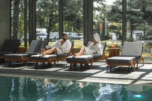 two people sitting in chairs next to a swimming pool at Crowne Plaza Belgrade by IHG in Belgrade