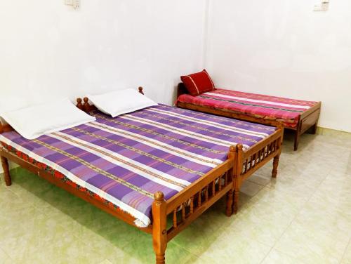 two beds sitting in a room with at Mylooran Hotel in Jaffna