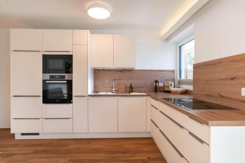 una cocina blanca con armarios blancos y fregadero en Waldrand Apartments en Ramsau am Dachstein