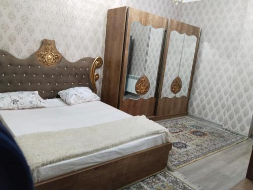 een slaapkamer met een bed met een houten hoofdeinde en een spiegel bij 2 Bedrooms Apartment on 28 May Metro in Baku