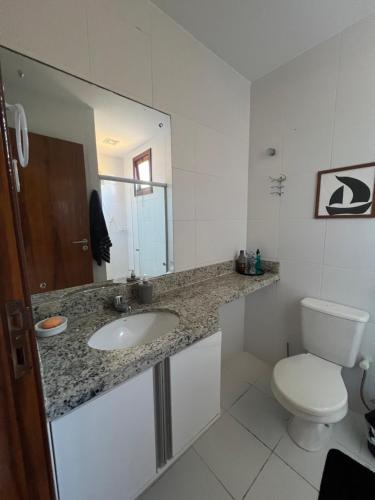 a bathroom with a sink and a toilet and a mirror at Casa da Sorte in Camacari