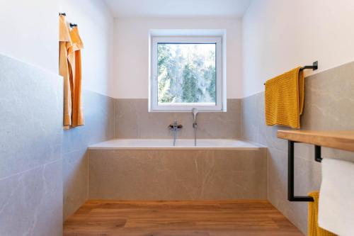 a bathroom with a tub and a window at Waldrand Apartments in Ramsau am Dachstein