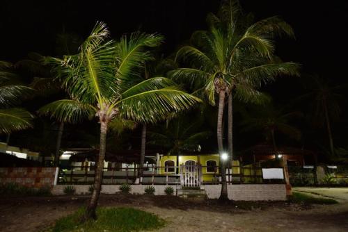 two palm trees in front of a house at night at Pousada Robijn in Cabo de Santo Agostinho