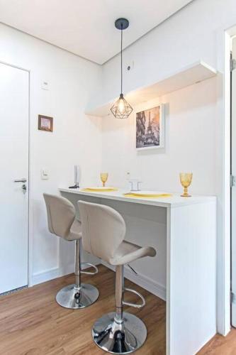 a white kitchen with a counter and two chairs at Studio Charmoso Alto da Boa Vista - Próx CGH e Transamérica in Sao Paulo