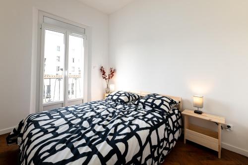 une chambre avec un lit noir et blanc et une fenêtre dans l'établissement Elégance méditerranéenne 3p, avec Parking, à Juan-les-Pins