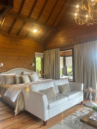 a large bedroom with a white bed and a couch at Vallée Cabanas in Urubici