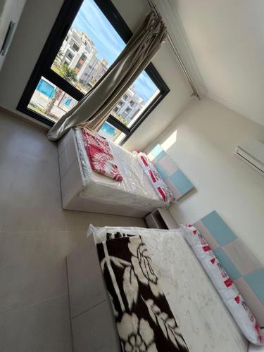 - une chambre mansardée avec 2 lits et une fenêtre dans l'établissement GAIA North Coast, à Marsa Matruh