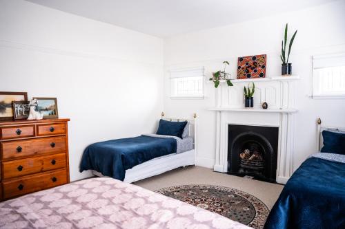 a bedroom with two beds and a fireplace at Charming 1920s Villa on Bealey Ave in Christchurch