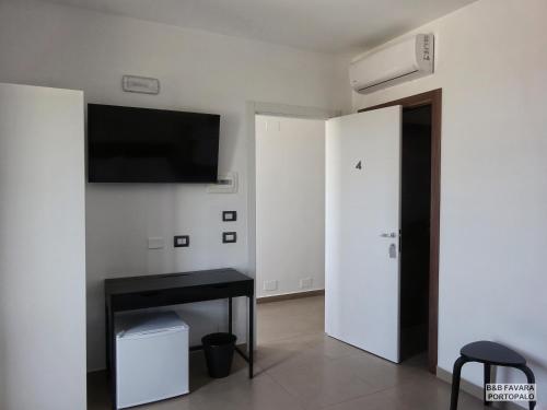 Cette chambre blanche dispose d'une table noire et d'une télévision à écran plat. dans l'établissement FAVARA Rooms, à Portopalo di Capo Passero