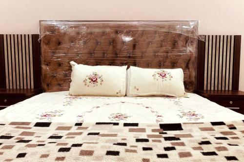 a bed with two pillows and a padded head board at Exotic Hill View Stay in Karachi
