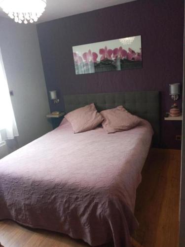 a bedroom with a large bed with pink sheets at 24 heures du Mans Chambre d'hôte avec piscine in La Suze-sur-Sarthe