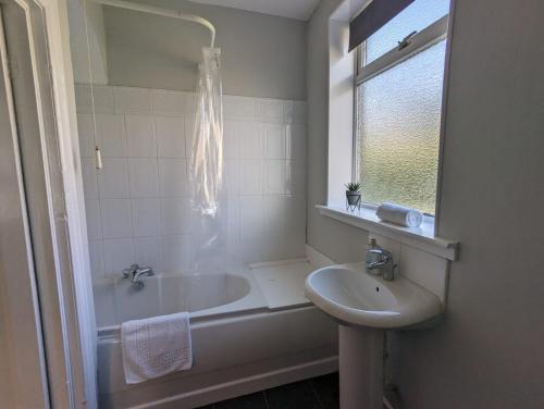 a bathroom with a tub and a sink and a window at Alexander Apartments High Heaton in Gosforth