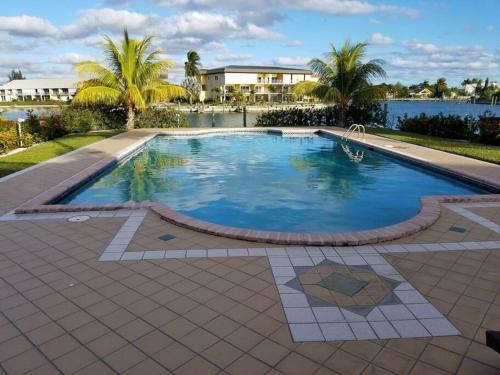 a large swimming pool with palm trees and water at Beautiful 3 Bed 3 & a half Bath Home with Pool & Dock Slip in Freeport