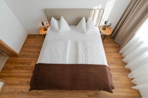 a bed with white sheets and pillows in a room at Waldrand Apartments in Ramsau am Dachstein