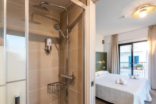 een badkamer met een douche en een bed in een kamer bij Hostal Alicante in San Antonio