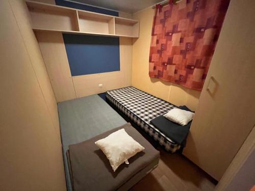 une petite chambre avec deux lits et une fenêtre dans l'établissement Mobil-Home avec belle exposition, à Saint-Chéron