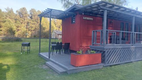 a red house with a table and chairs on a deck at Pids randõ in Kolka