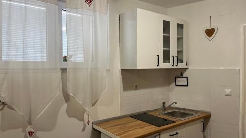 a kitchen with white cabinets and a sink and a window at Apartment Kova in Split