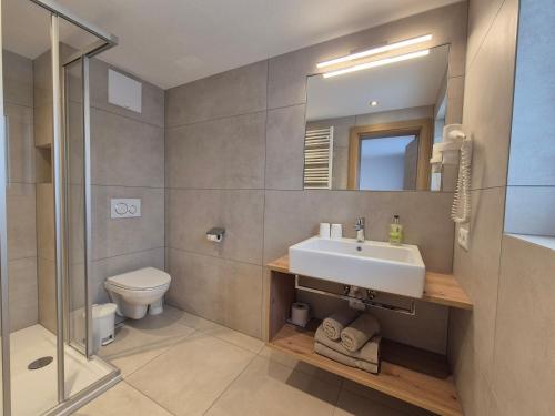 ein Badezimmer mit einem Waschbecken, einem WC und einem Spiegel in der Unterkunft Pension Gabl in Pfunds