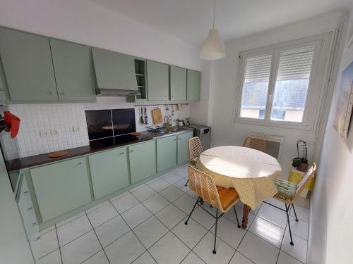 une cuisine avec des armoires vertes, une table et des chaises dans l'établissement Larmor-Plage T2 Notre-Dame, à Larmor-Plage