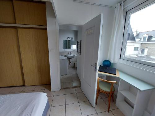 Cette petite chambre comprend un lit, un bureau et une fenêtre. dans l'établissement Larmor-Plage T1bis Notre-Dame, à Larmor-Plage
