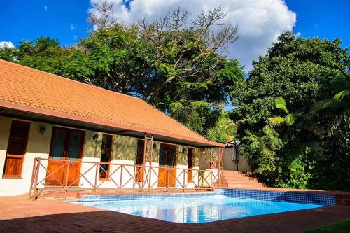 a swimming pool in front of a building with trees at RIETONDALE LODGE in Pretoria