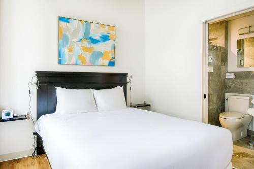 1 dormitorio con cama blanca y aseo en Les Lofts de Buade - Par Les Lofts Vieux-Québec, en Quebec