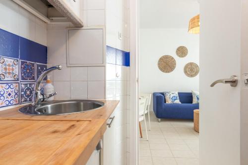 een keuken met een wastafel en een blauwe bank bij Apartamento en Tossa de Mar a 3 min de la playa in Tossa de Mar