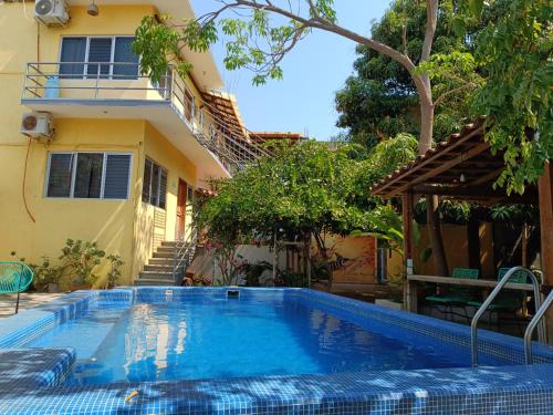 a swimming pool in front of a house at Paziflora Hostel in Puerto Escondido