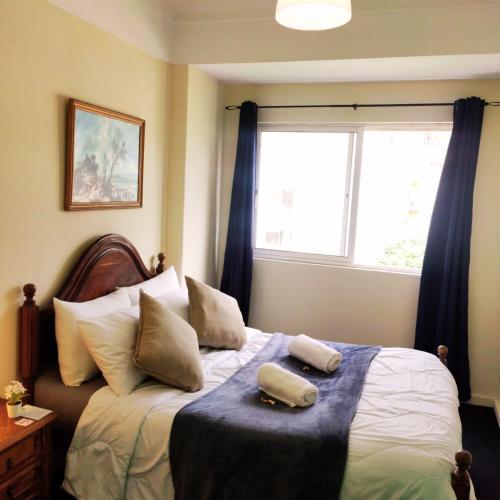 a bedroom with a bed with two pillows and a window at Liberdade Home Royal direito in Braga