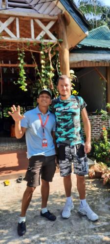two men standing next to each other in front of a building at Wisma Batu Mandi in Bukit Lawang