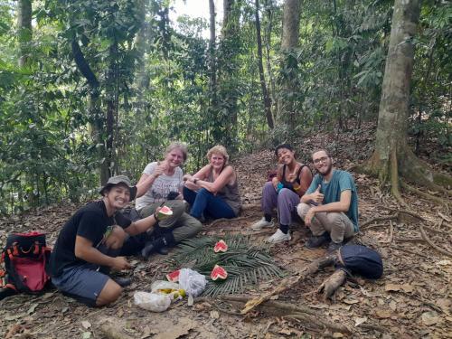 a group of people sitting on the ground in the forest at Wisma Batu Mandi in Bukit Lawang