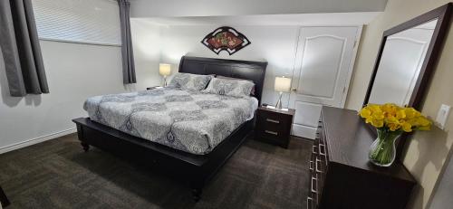 1 dormitorio con 1 cama y un jarrón de flores en Comfy KING Bed, Large private Basement Suite, Smart TV in Penticton- city of PEACHES AND BEACHES en Penticton